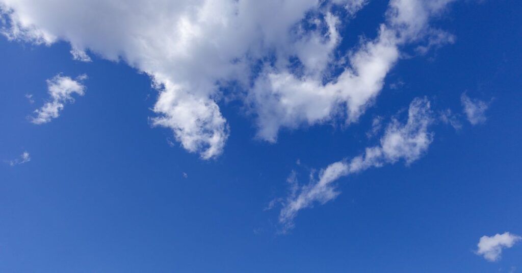 空に浮かぶ龍神雲を静かに撮影する人、光が雲を照らし神秘的に輝くスピリチュアルな風景